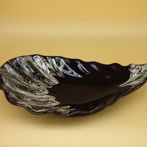 May include: A black ceramic serving dish with a wavy edge and a green and white marbled design.