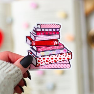 May include: A stack of books with pink and red covers featuring hearts, XOXO, and the words "LOVE SPELL" and "DO LOVE".