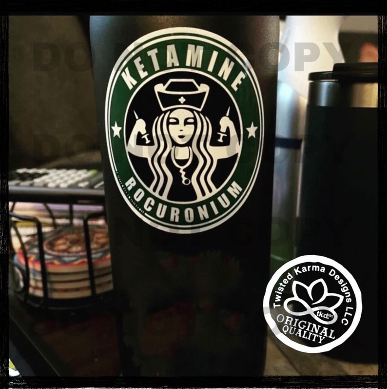 May include: Black and green tumbler with a white sticker featuring a stylised image of a woman with a nurse's cap and stethoscope, holding syringes. The sticker says "KETAMINE ROCURONIUM".