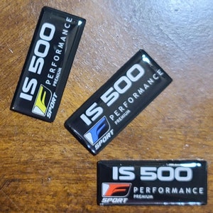 May include: Four black and white rectangular stickers with the text "IS 500 PERFORMANCE PREMIUM SPORT" on them. The stickers are on a wooden surface.