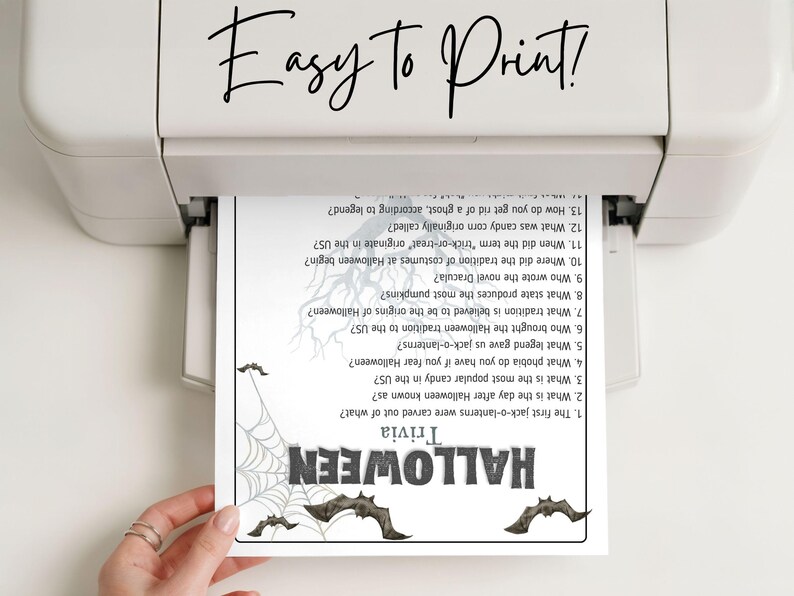 May include: A printed Halloween trivia sheet emerges from a printer. The sheet features a spiderweb and bat graphics, with the word "HALLOWEEN" in bold letters. The text "Easy to Print!" is at the top.