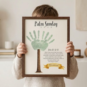 Pode incluir: Uma impressão emoldurada com um design de impressão de mão representando uma palmeira. O texto "Palm Sunday 2026" está no topo, com um versículo bíblico e a palavra "Hosanna!" abaixo. A moldura é marrom.
