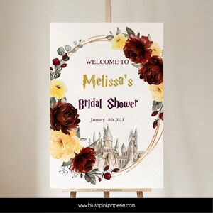 Pode incluir: Um sinal de chá de panela imprimível com uma grinalda floral em aquarela, um castelo de glitter dourado e o texto "Bem-vindo ao chá de panela da Melissa, 18 de janeiro de 2023".