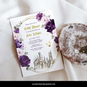 May include: Purple and pink floral bridal shower invitation with a gold border and a watercolor illustration of Hogwarts castle. The text reads "Please join us for a Bridal Shower honoring the bride to be Amy Wilson 03.13.2023 | 3 P.M. The Location Name 123 Street Address Sample City Name ST - 12345 Registered at: Bed bath an Beyond Please RSVP to Hanna at 123.456.7890 www.blushpinkpaperie.com"