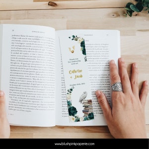 Könnte beinhalten: Ein Lesezeichen mit einem Aquarelldesign, das eine weiße Eule zeigt, die auf einem Stapel Bücher sitzt, einen goldenen Schnatz und grüne und weiße Blumen. Das Lesezeichen trägt den Text "Thank you for celebrating with us! Catherine + Jacob October 25th, 2025".