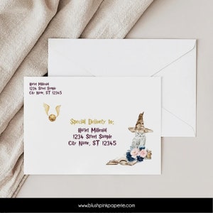 May include: A white envelope with a gold and purple address label. The address reads "Hariet Millenial, 1234 Street Sample, City Name, ST 12345". The envelope has a watercolor illustration of a white owl wearing a brown and black wizard hat, holding a book. The owl is sitting on a stack of books with pink and blue flowers. The envelope also has a gold illustration of a golden snitch.