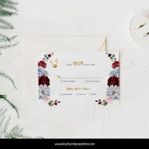 May include: A white RSVP card with a floral border in shades of burgundy, blue, and pink. The card features a gold snitch and the text "PLEASE RSVP BY JULY 22ND". The card has checkboxes for "Will be there" and "Sad to miss it!" and a section for "Main course choice" with options for "Vegetarian", "Poultry", and "Beef".