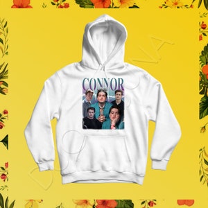May include: White hoodie with a graphic print of a group of young men. The graphic features the word "CONNOR" in large, purple letters.