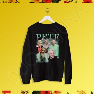 May include: Black sweatshirt with a graphic print of Pete Davidson. The print features a collage of photos of Davidson with the text "Pete Davidson" in a green and white font.