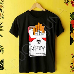 May include: Black t-shirt with a graphic of a cigarette pack with the text "Suicideboys" printed on it.