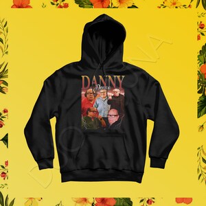 May include: Black hoodie with a vintage-style graphic of Danny Devito and the words "Danny Devito" in a yellow and orange font.