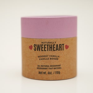 以下が含まれることがあります： ピンクと茶色の紙筒に、黒い文字で「NATURALLY SWEETHEART」と赤いハートが2つ書かれている。その下に黒い文字で「WOODSY VANILLA VANILLE BOISÉE」と印刷されている。「ALL NATURAL DEODORANT DEODORANT TOUT NATUREL」という文字が黒で印刷されている。「Net wt. 4oz./110g」という文字が黒で印刷されている。