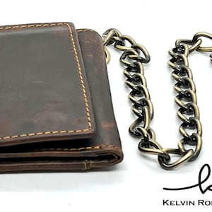May include: A brown leather wallet with a chain attached. The chain is made of metal and has a clasp. The wallet has a distressed look and is folded closed. The text "Kelvin Rolen Leather" is visible at the bottom of the image.
