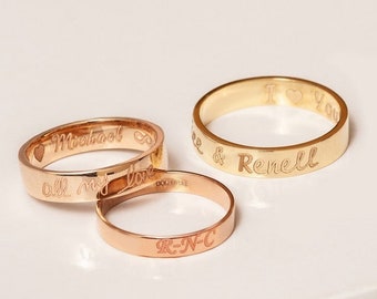 Könnte beinhalten: Drei goldene Ringe mit gravierten Botschaften. Der obere Ring trägt die Inschrift "Ich liebe dich" und "Renee & Renell". Der mittlere Ring trägt die Inschrift "Michael" und "all meine Liebe". Der untere Ring trägt die Inschrift "R-N-C".