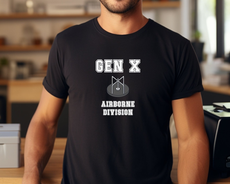 May include: Black t-shirt with white text that reads "GEN X AIRBORNE DIVISION". The text is in a collegiate font style. A stylized image of a parachute is above the text.