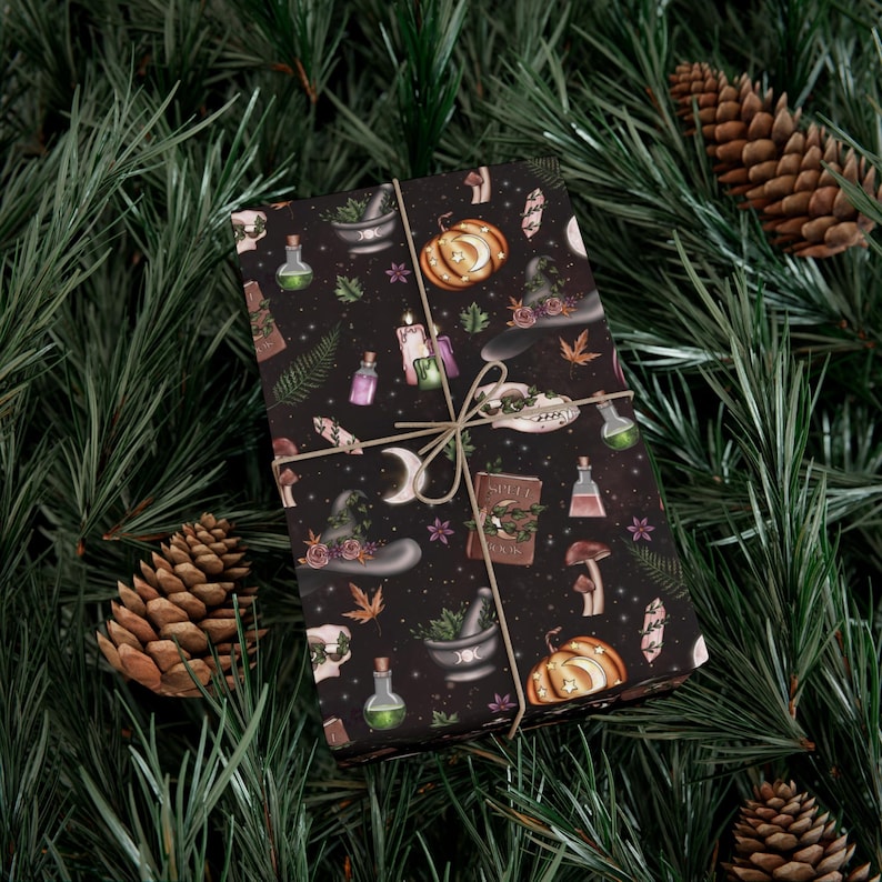 May include: Witchcraft-themed gift wrap features a dark background with illustrations of pumpkins, moons, crystals, potions, and a spell book.  The design also includes various herbs and botanical elements in shades of green and purple.  The text on the book says 'Spell Book'. The wrapping paper is tied with twine, creating a visually appealing presentation suitable for Halloween or autumnal celebrations.