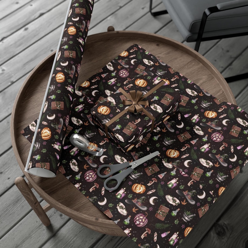 May include: A black and brown gift wrap with a repeating pattern of witchy items, including cauldrons, potion bottles, pumpkins, and moons. The wrap is shown rolled up and wrapped around a gift box.