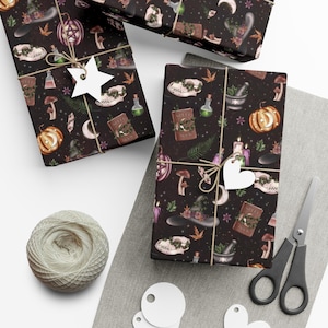 May include: Black and white wrapping paper with a witchy theme. The paper features a repeating pattern of skulls, potion bottles, mushrooms, pumpkins, and other witchy items. The paper is wrapped around a gift box and tied with twine.