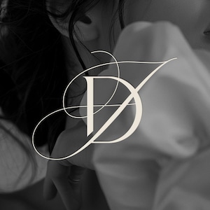 May include: A black and white photo of a person with long hair, wearing a white shirt with a stylized monogram of the letters "D" and "Y" in a script font.