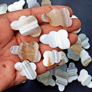Pode incluir: Uma coleção de pedras de ágata em forma de borboleta, de cor branca e marrom. As pedras têm um padrão natural estriado.
