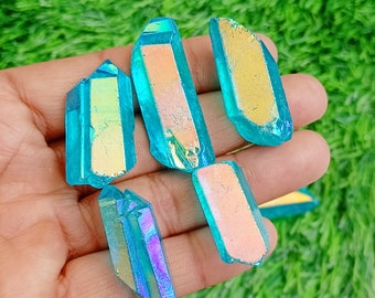 May include: Five iridescent blue and green crystal points with a rainbow sheen. The crystals are arranged on a hand.
