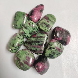 Puede incluir: Una colección de nueve piedras de zoisita verde y rosa pulidas. Las piedras son lisas y pulidas, con una variedad de patrones y colores.