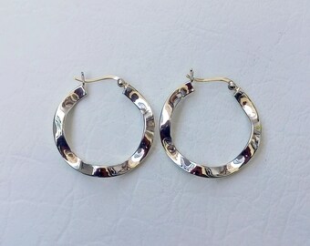 May include: A pair of silver hoop earrings with a hammered texture.