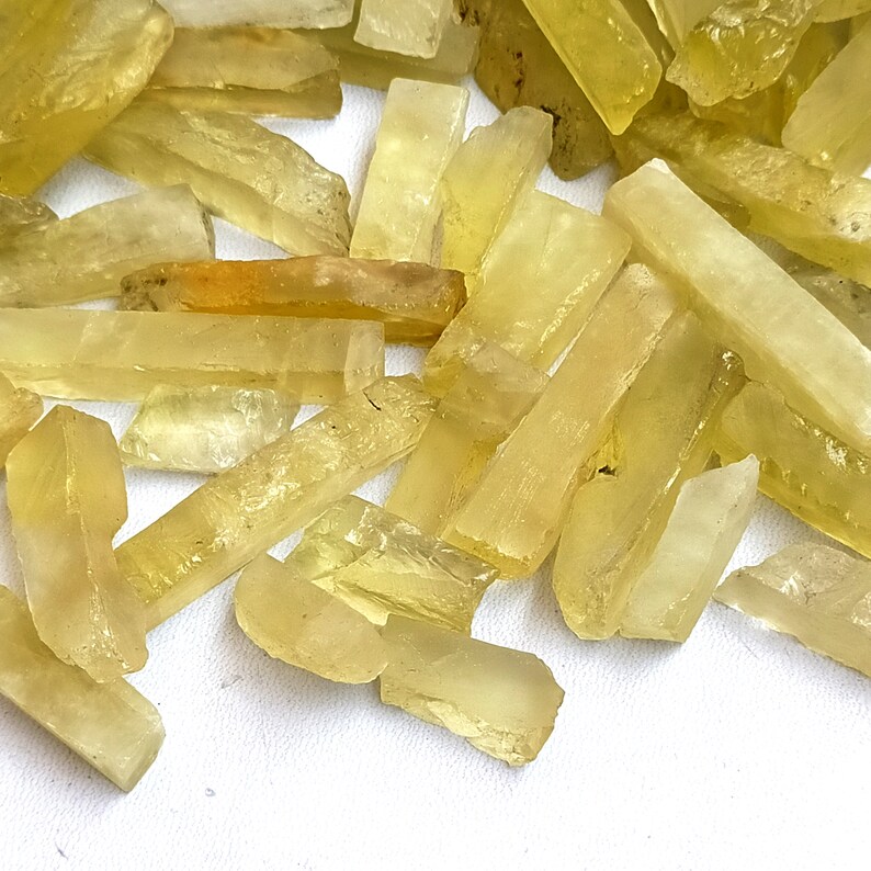 Puede incluir: Un mont&oacute;n de cristales rectangulares transl&uacute;cidos de color amarillo. Los cristales son lisos y tienen un aspecto natural y en bruto.