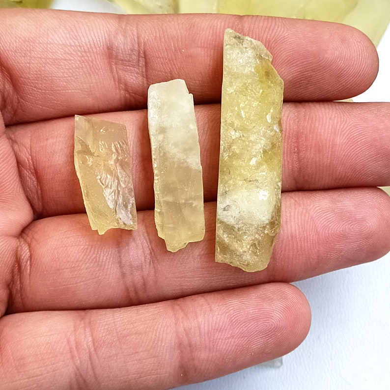 Puede incluir: Tres puntas de cristal de color amarillo, de diferentes tama&ntilde;os, con una textura rugosa y natural. Los cristales se sostienen en la mano de una persona.