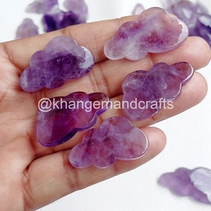 May include: A collection of seven purple amethyst gemstone cloud shaped carvings. The carvings are smooth and polished.