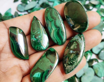 Pode incluir: Uma coleção de seis cabochões de malaquita verde em vários formatos e tamanhos. Os cabochões são lisos e polidos, com uma variedade de tons e padrões verdes.