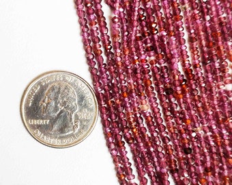 May include: A strand of deep red gemstone beads, likely ruby or garnet, with a faceted finish. The beads are small and uniform in size, and the strand is long enough to be used for jewelry making.