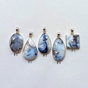 May include: Five dendritic opal pendants with silver-colored bails. The pendants vary in shape, including oval, teardrop, and square. Each pendant features a unique pattern of white, gray, and black inclusions within the opal.