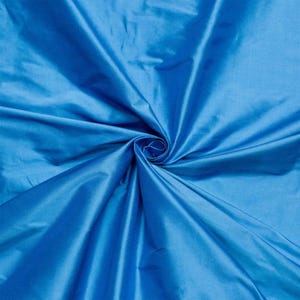 May include: A close-up of a smooth, bright blue fabric. The fabric is folded and draped, showing its texture and colour.