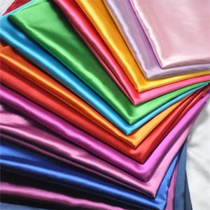 Peut inclure: Un assortiment d'échantillons de tissu satiné de différentes couleurs, notamment du vert, du bleu, de l'orange, du rouge, du violet et du rose.