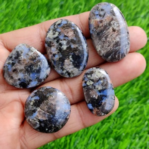 Könnte beinhalten: Fünf glatte, polierte Steine mit einem blauen, schwarzen und weißen Marmormuster. Die Steine sind oval und rund.