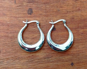 May include: A pair of silver hoop earrings with a curved, rounded shape.