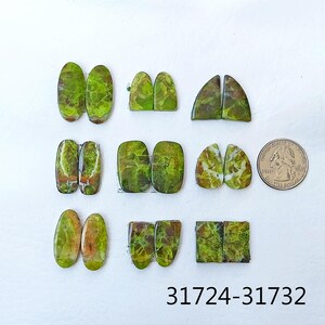 May include: A set of 10 green and white cabochons, some oval, some rectangular, some teardrop shaped. The cabochons are arranged in rows on a white surface. A US quarter is included for scale.