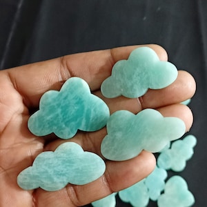Puede incluir: Una colección de cabujones en forma de nube de amazonita verde y azul. Los cabujones son lisos y pulidos.