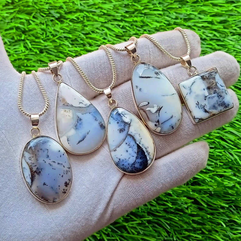 May include: Five silver-toned pendant necklaces with dendritic agate stones. The pendants have various shapes: oval, teardrop, and square. The stones feature a mix of white, gray, and black patterns. The necklaces are displayed on a light-colored surface against a green background.