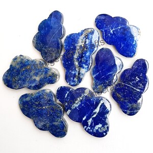 Pode incluir: Oito cabochões de lapis-lazúli azul em forma de nuvem. As pedras têm uma cor azul profunda com veios brancos e dourados.