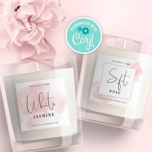 May include: Two glass candle jars with labels. The candle on the left is labeled "White Jasmine" and the candle on the right is labeled "Soft Rose". Both candles are made in California and are 8 oz.