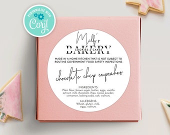 May include: A pink and white box with a round sticker that says "Milly's Bakery Cookies & Cakes" and "chocolate chip cupcakes". The sticker also includes the text "Made in a home kitchen that is not subject to routine government food safety inspections". The sticker also lists the ingredients and allergens.