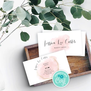 May include: Two business cards with a pink watercolor background and gold glitter accents. The text on the cards reads "Jessica Lee Carter" and "Makeup Artist". The cards also include social media handles, a website address, and a phone number. The cards are in a wooden box.