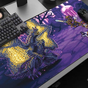 May include: A large rectangular mouse pad featuring a pixelated dragon with yellow and blue accents. The design includes pixelated characters and a purple background. A black keyboard and mouse are visible.