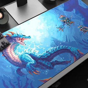 以下が含まれることがあります： 青いドラゴンとオレンジ色のアクセントのピクセル化されたイラストが描かれた、大きな長方形のマウスパッド。背景は、ピクセル化された人物がいる濃い青色です。キーボードとスピーカーが見えます。