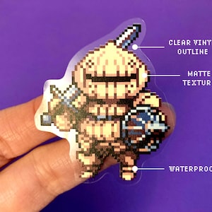May include: A clear vinyl sticker with a matte finish featuring a pixelated illustration of a knight in armor holding a sword and shield. The sticker is waterproof.