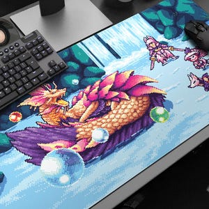 May include: A pixelated gaming mouse mat featuring a colourful dragon with pink, orange, and yellow scales, surrounded by pixelated characters and bubbles. The design has a retro video game aesthetic, with a keyboard and mouse visible.