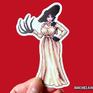 May include: A sticker featuring a pixelated illustration of a woman in a white dress and black hat holding a set of sharp claws. The woman has long black hair and is wearing a necklace.