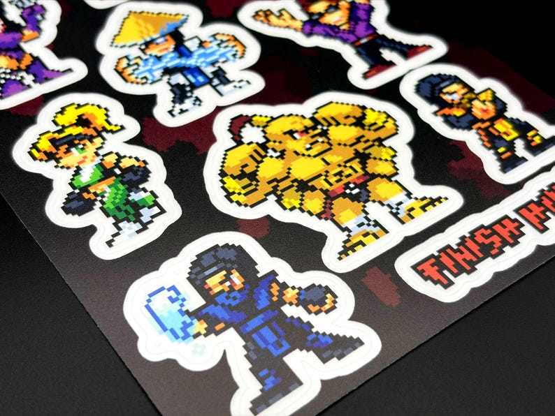 May include: Sheet of pixel art stickers featuring various video game characters in action poses. The stickers are colorful with a white border and are on a black background. The text "FINISH HIM" is visible.